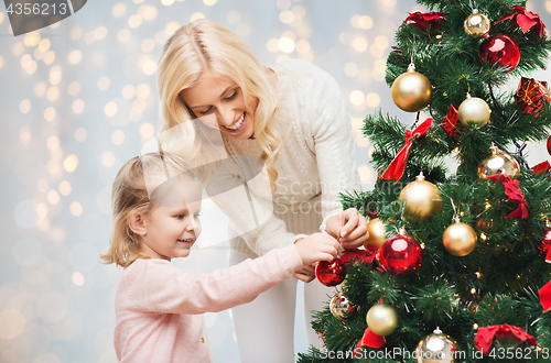 Image of mother and daughter decorating christmas tree