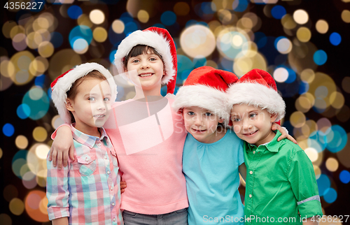 Image of happy little children in santa hats hugging