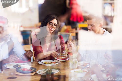 Image of happy friends eating at restaurant