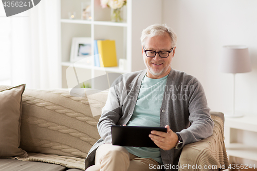 Image of senior man with tablet pc sitting on sofa at home