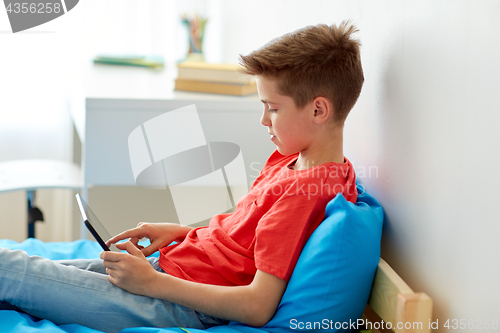 Image of smiling boy with tablet pc computer at home