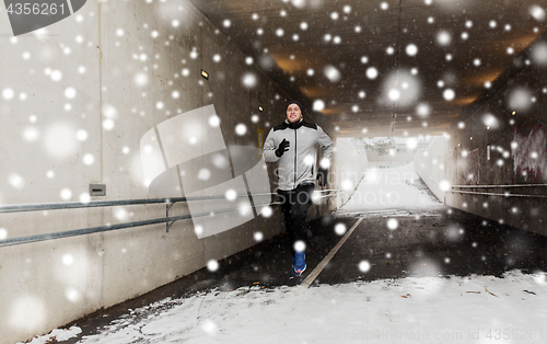 Image of happy man running along subway tunnel in winter