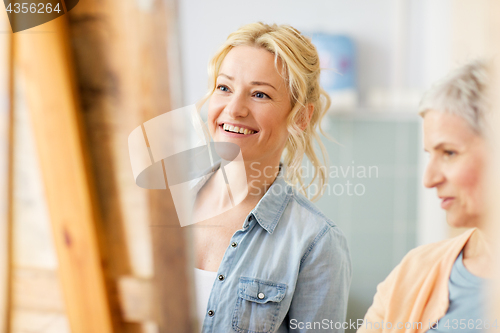 Image of artists discussing painting on easel at art school