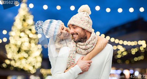 Image of happy couple hugging over christmas tree lights