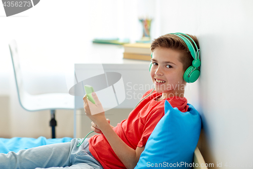 Image of happy boy with smartphone and headphones at home