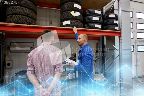 Image of auto mechanic and man with tires at car shop