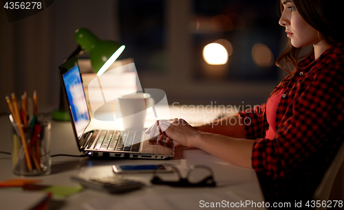 Image of student or woman typing on laptop at night home