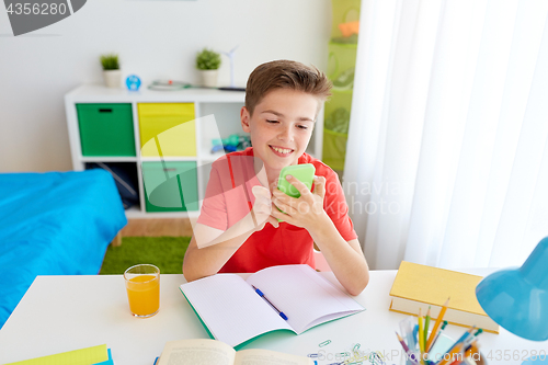 Image of student boy with smartphone distracting from study