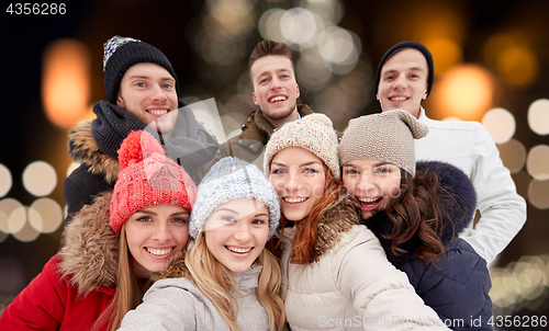 Image of happy friends taking selfie outdoors at christmas