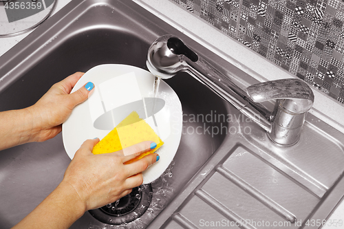 Image of woman that washes a white dish