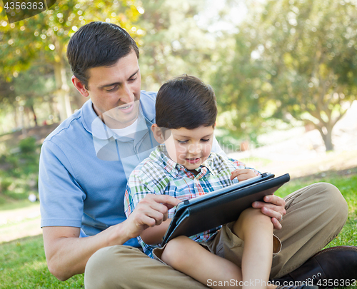 Image of Happy Father and Son Playing on a Computer Tablet Outside.