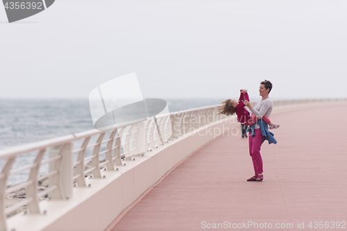 Image of mother and cute little girl on the promenade by the sea