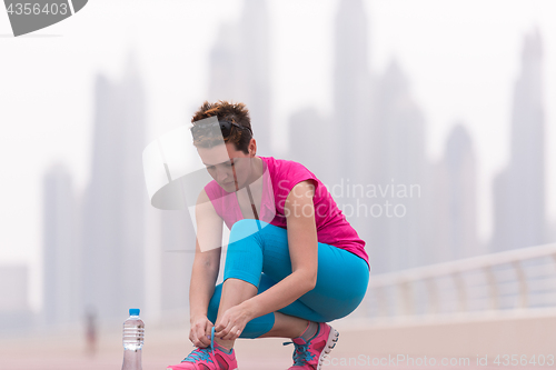 Image of woman tying shoelaces on sneakers