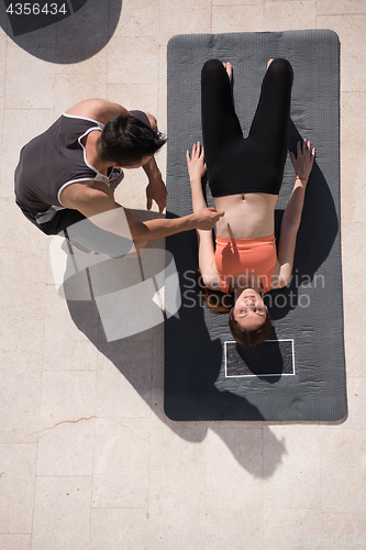 Image of woman with personal trainer doing morning yoga exercises top vie