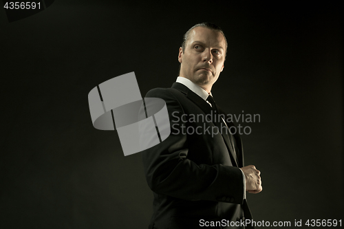 Image of The attractive man in black suit on dark background