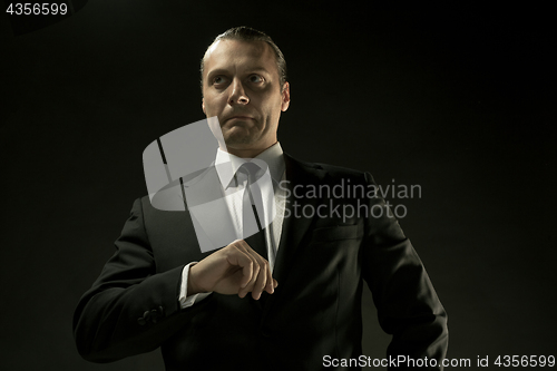 Image of The attractive man in black suit on dark background