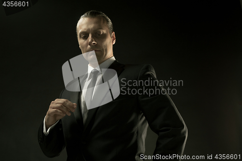 Image of The attractive man in black suit on dark background