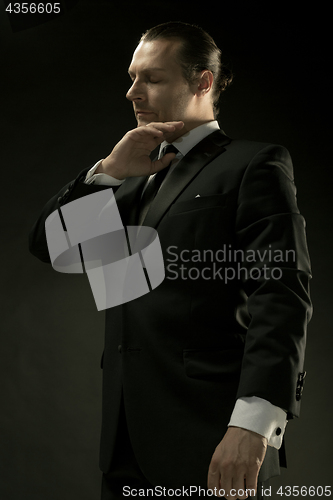 Image of The attractive man in black suit on dark background