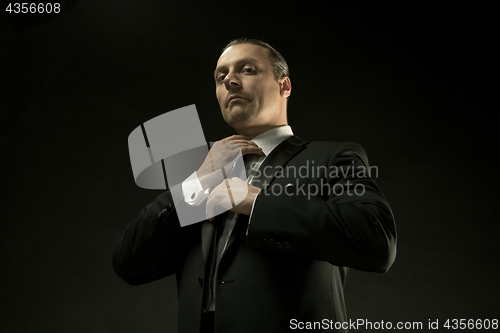 Image of The attractive man in black suit on dark background