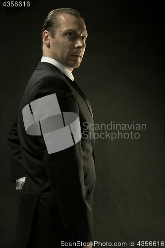 Image of The attractive man in black suit on dark background