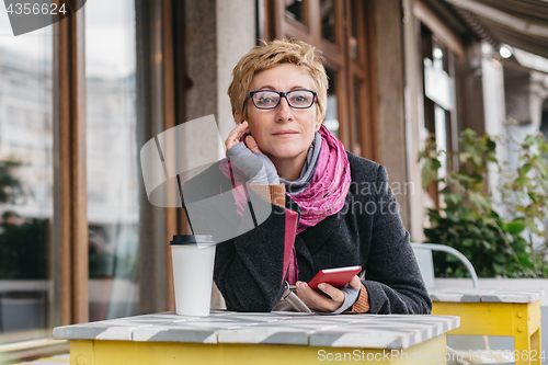 Image of Dreamy woman with phone in cafe