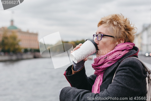 Image of Woman drinking coffee on waterfront