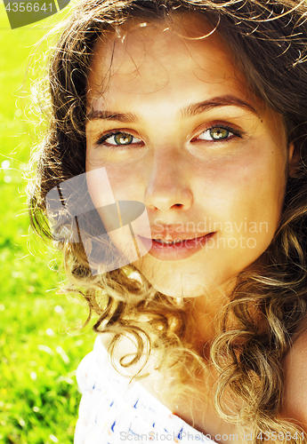 Image of young cute summer girl on green grass outside relaxing smiling close up