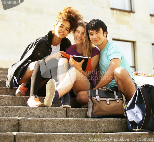 Image of cute group of teenages at the building of university with books huggings, back to school