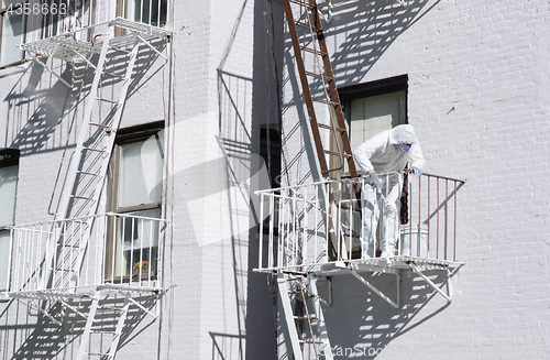 Image of Building painter painting metal fire escapes white