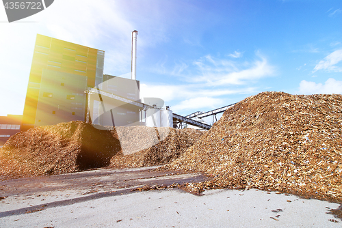 Image of bio power plant with storage of wooden fuel against blue sky