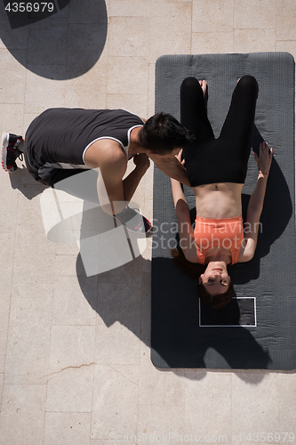 Image of woman with personal trainer doing morning yoga exercises top vie