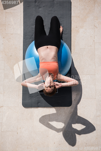 Image of woman doing exercise with pilates ball top view