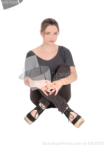 Image of Serious looking woman sitting with closed legs on floor