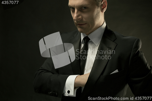 Image of The attractive man in black suit on dark background