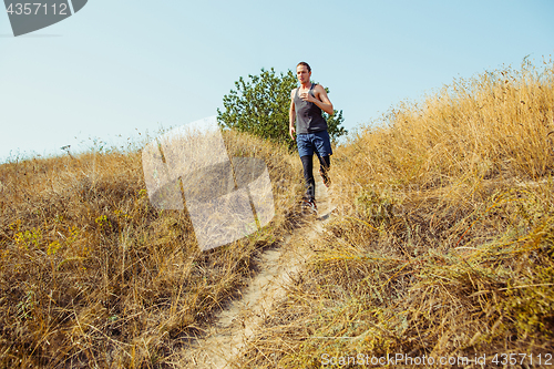 Image of Running sport. Man runner sprinting outdoor in scenic nature. Fit muscular male athlete training trail running for marathon run.