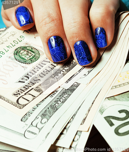 Image of close up fingers with deep blue creative pattern manicure holding dollars