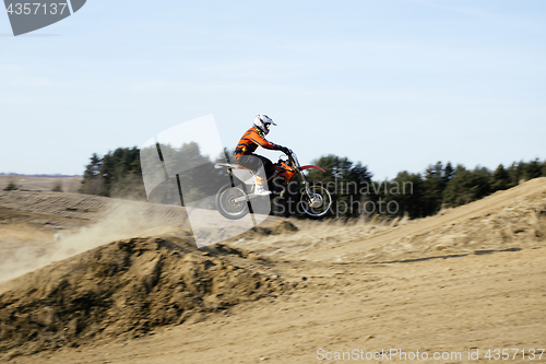 Image of motorcycle jump from springboard in meadow outside