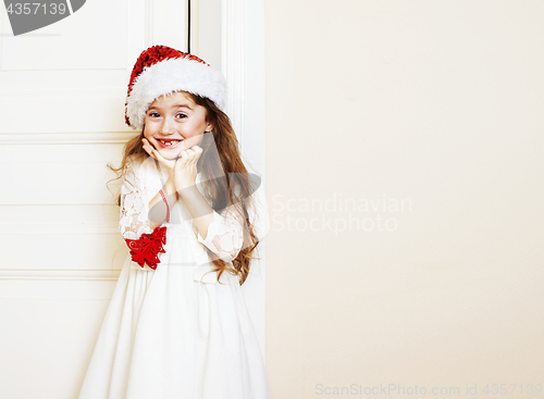 Image of little cute girl in santas red hat waiting for Christmas gifts. 