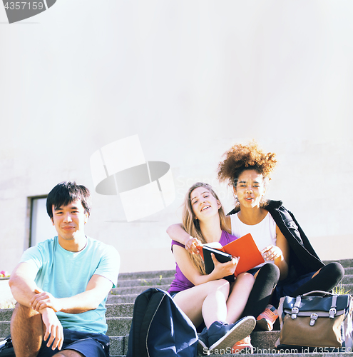 Image of cute group of teenages at the building of university with books huggings, back to school