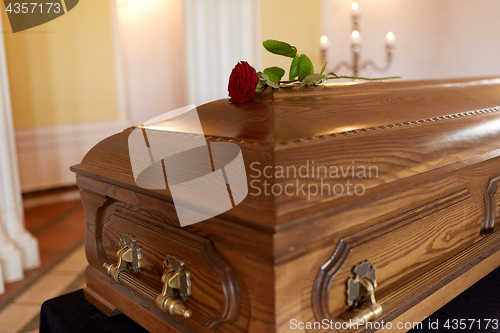 Image of red rose flower on wooden coffin in church