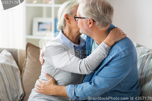 Image of close up of happy senior couple hugging at home