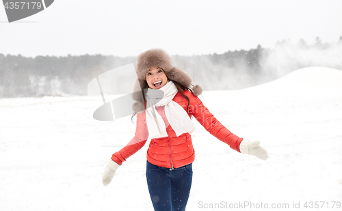 Image of happy woman in winter fur hat having fun outdoors