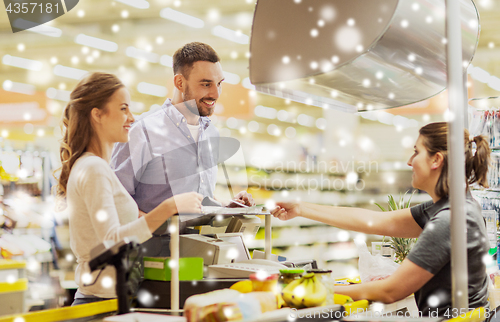 Image of couple buying food at grocery store cash register