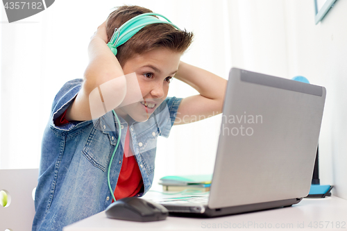 Image of boy in headphones playing video game on laptop