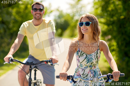 Image of happy young couple riding bicycles in summer