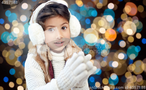 Image of girl in winter earmuffs over holidays lights