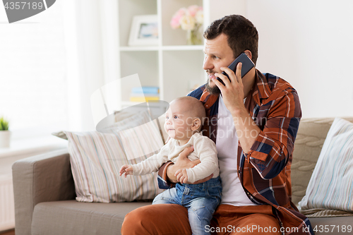 Image of father with baby calling on smartphone at home