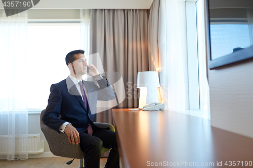 Image of businessman calling on smartphone at hotel room