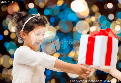 Image of smiling little girl giving or receiving present