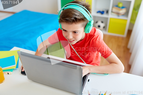 Image of boy in headphones playing video game on laptop